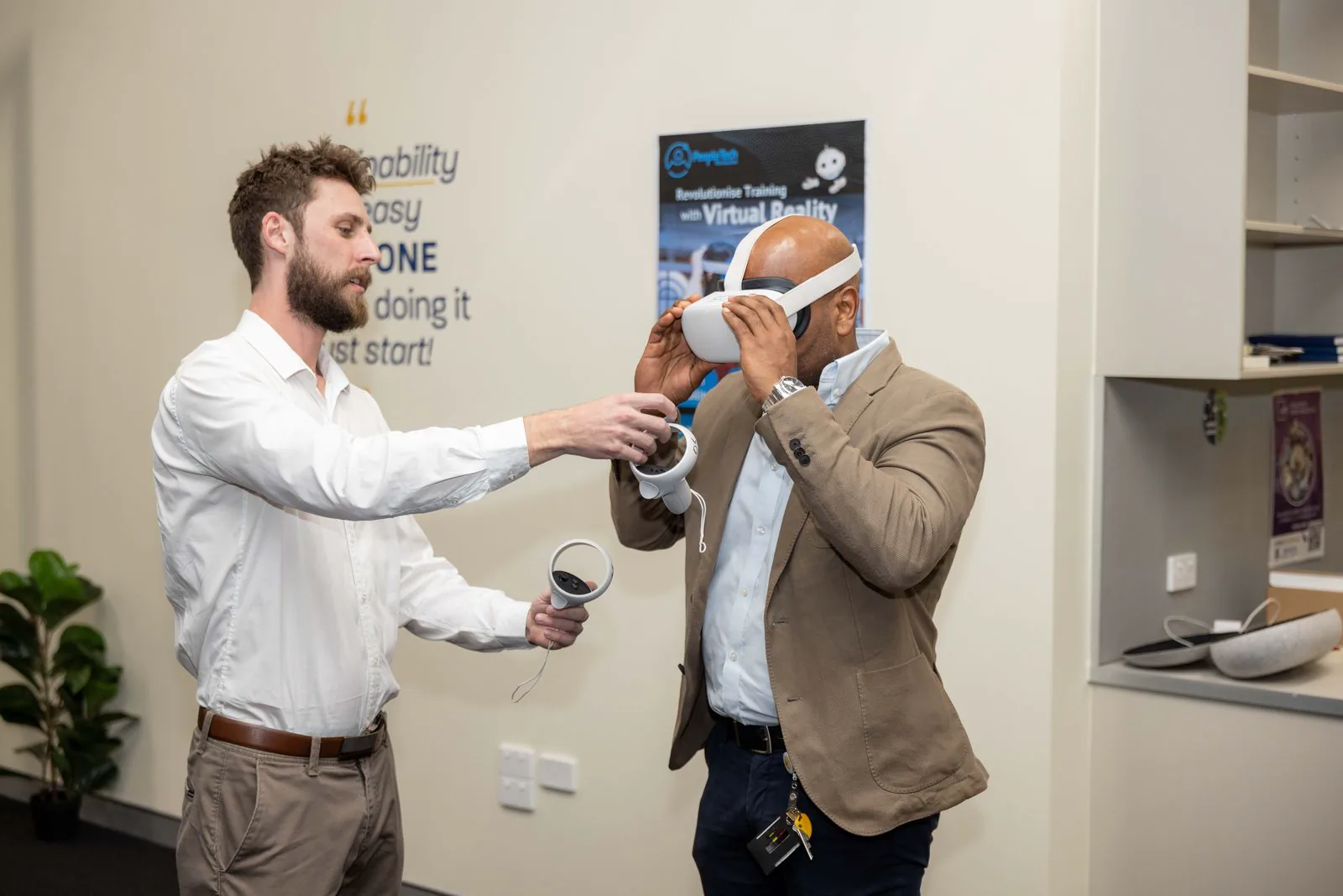 A facilitator fits a first-time user with a PTR-branded Meta Quest 2 headset at a live event, PTR's robot-character poster in the background.