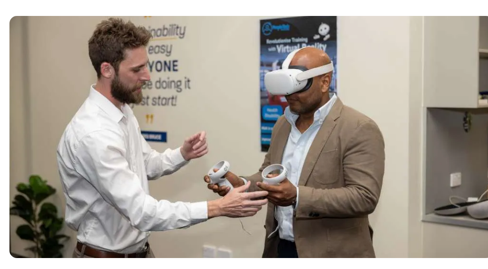 Photo of two men, one wearing a VR headset and holding controllers, during an Etihad cabin crew inclusion training session