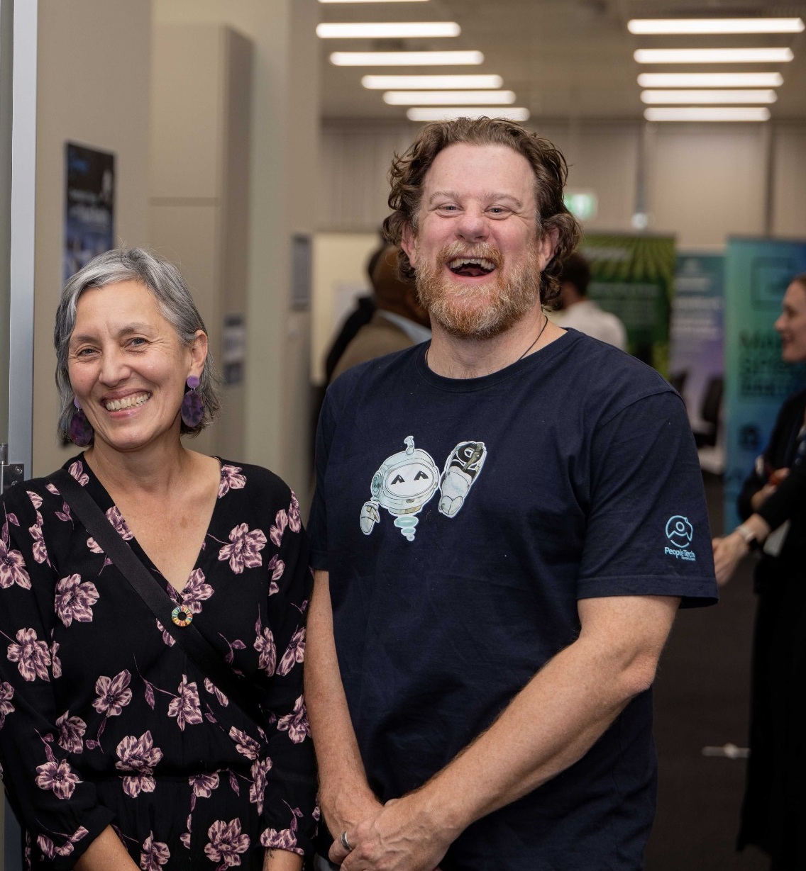 PTR co-founders Leonie Sanderson and Simon Lowe smiling together at an industry event, Simon wearing a PTR-branded t-shirt