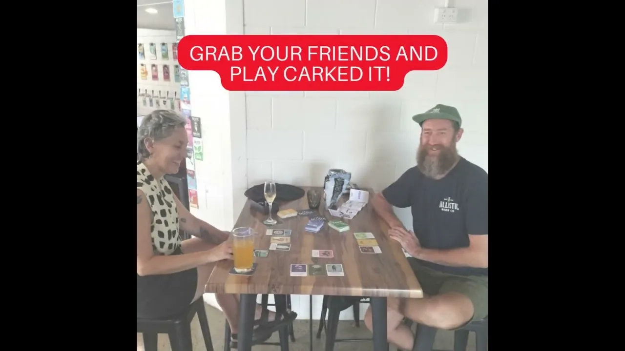 Two people at a pub table with the Carked It! cards between their glasses, the opening frame of the pub gameplay clip.
