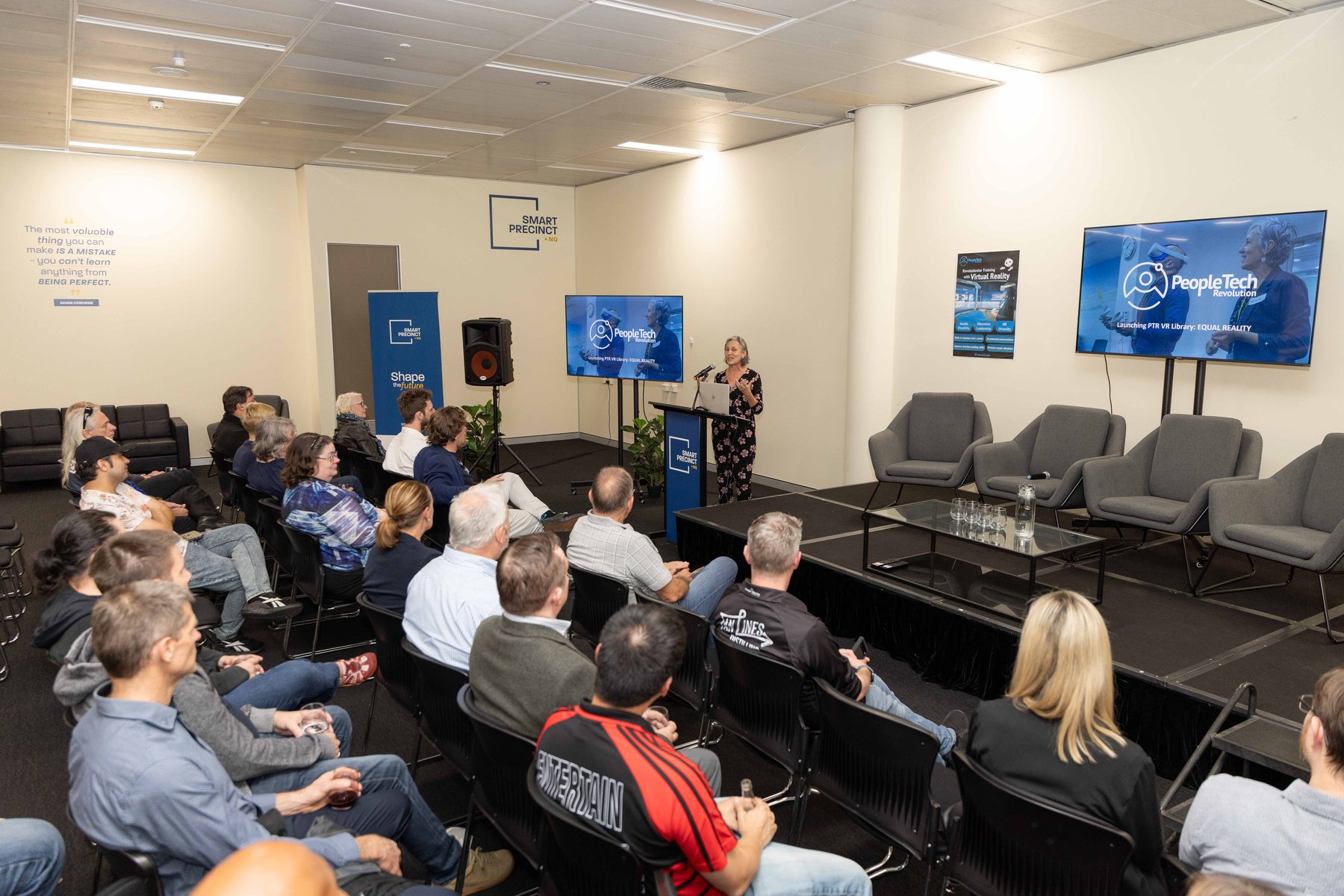 A full room of seated guests watches a presentation at the launch of the PTR VR Library, with PeopleTech Revolution slides on two screens