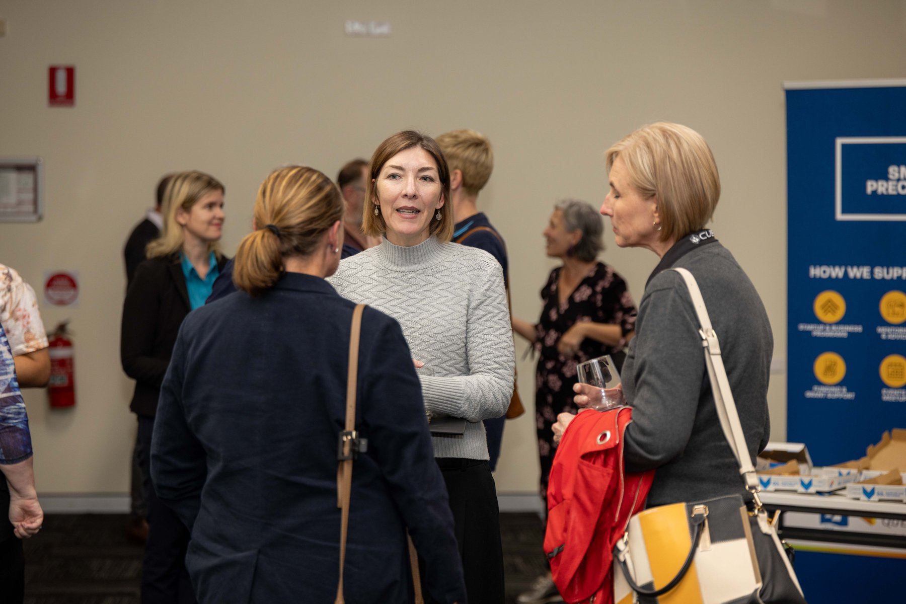 Guests chatting in small groups at a PTR community event, with a Smart Precinct banner in the background