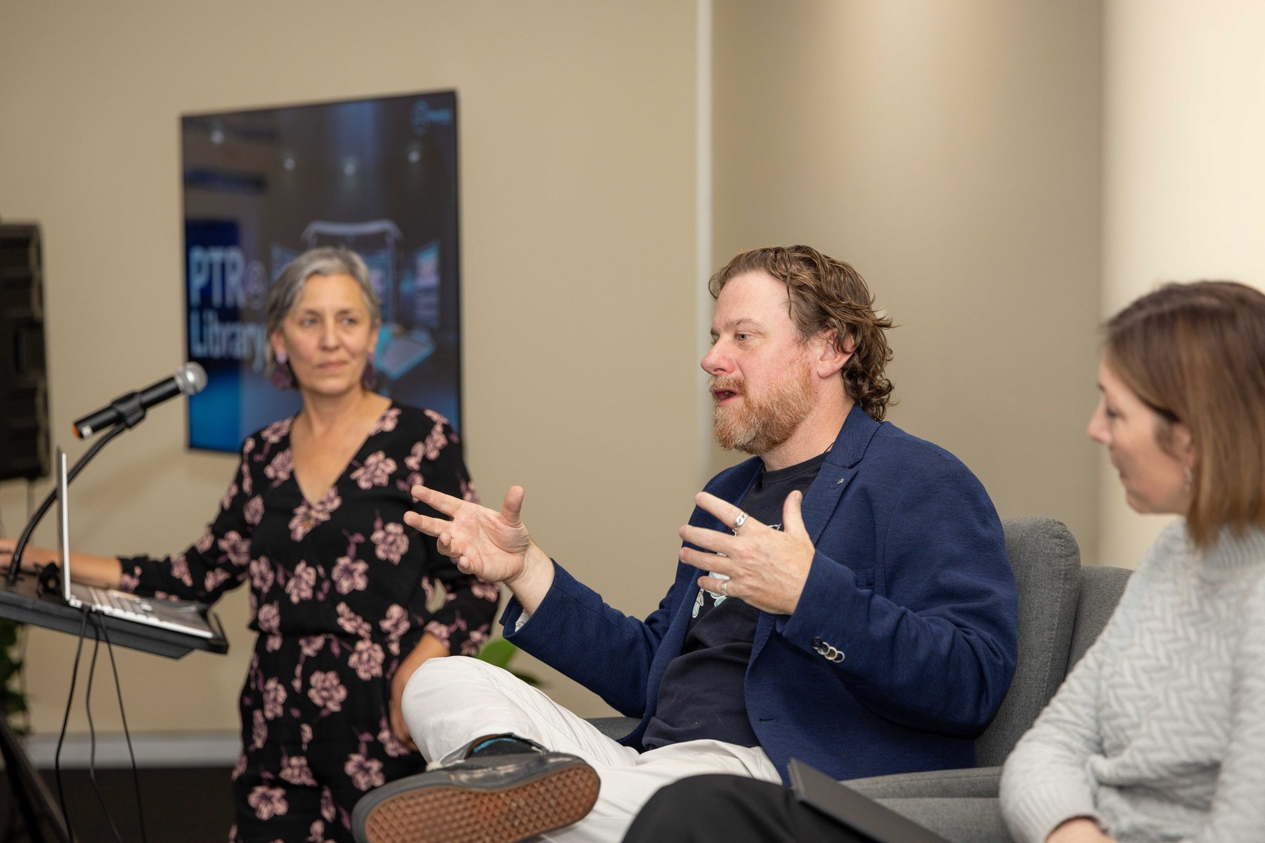 Leonie Sanderson speaking animatedly on a panel at a PTR community event, with fellow panellists listening
