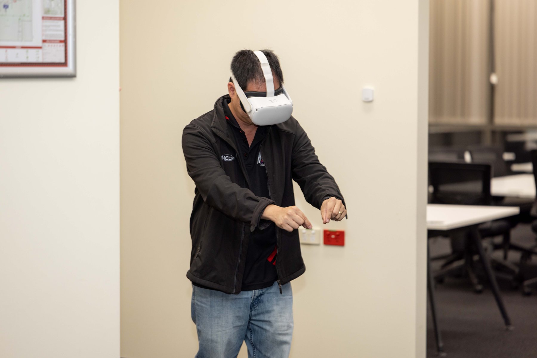 A man wearing a headset gestures with both hands mid-air while trying an immersive demo at a PTR community event