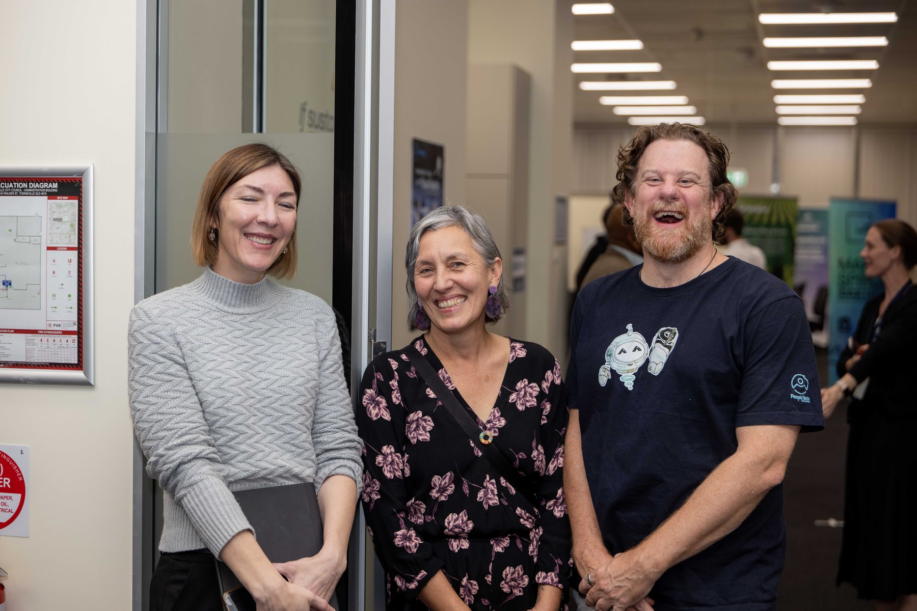 Three guests share a laugh together in a hallway at a PTR community event