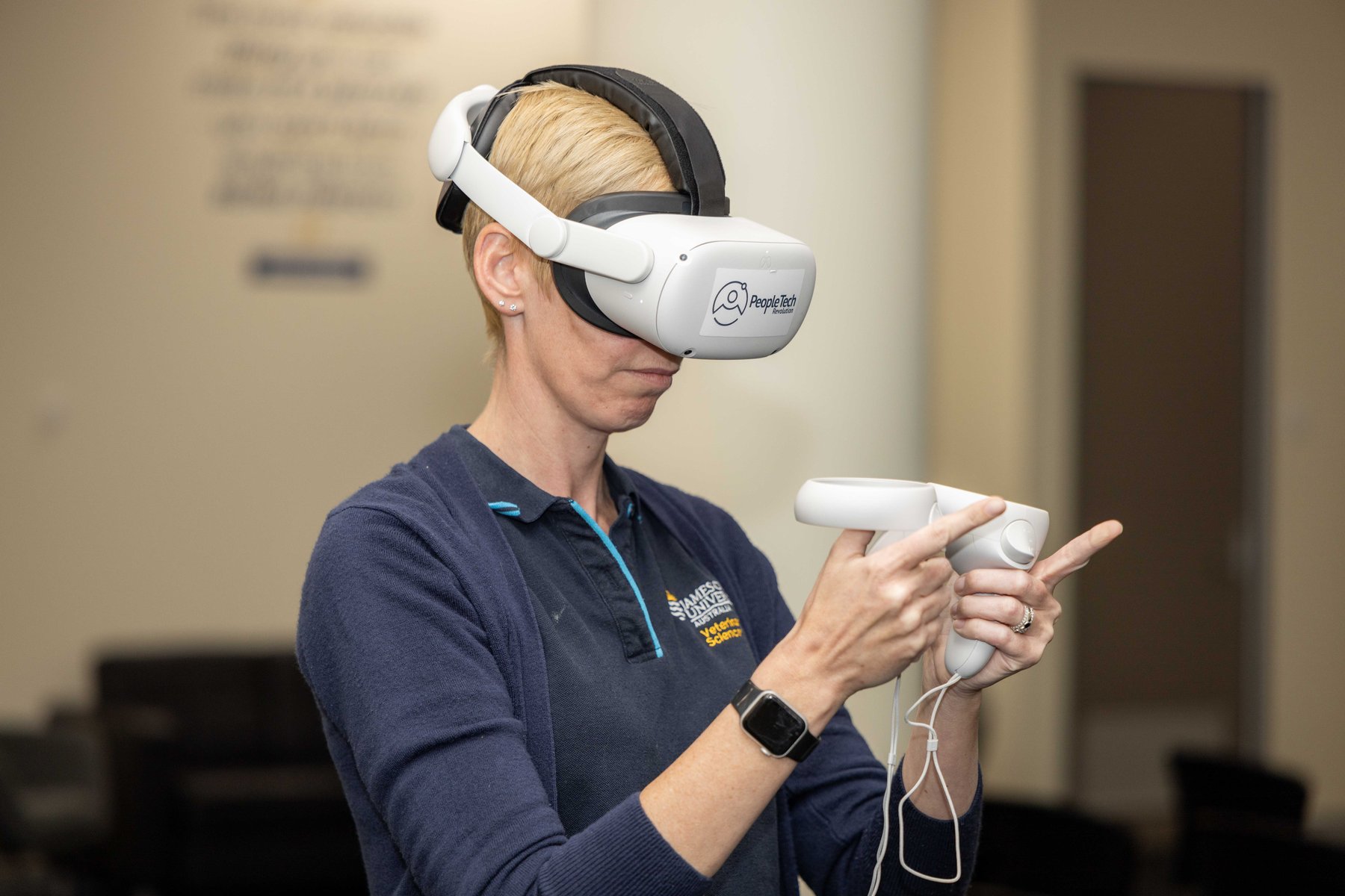 A woman wearing a PeopleTech Revolution branded headset points a controller while trying a demo at a PTR community event