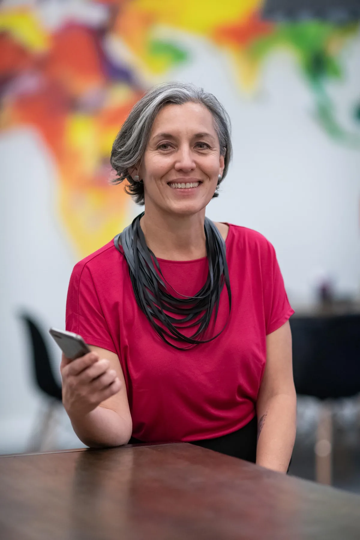 Leonie Sanderson, co-founder of People Tech Revolution, seated at a table with her phone in hand.