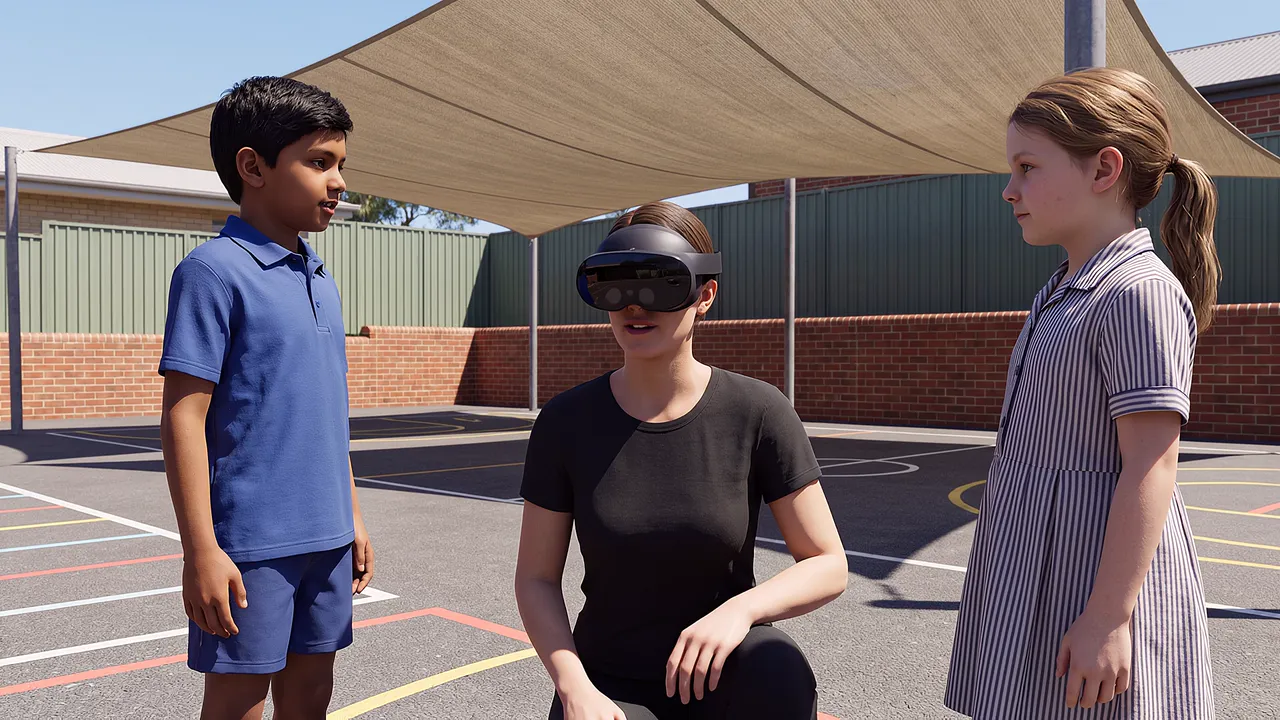 A simulated primary school playground under a shade sail. A teacher wearing the headset crouches between two children.
