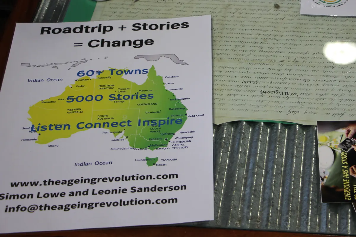 A flyer on a library table reads Roadtrip plus Stories equals Change above a map of Australia, the words Listen Connect Inspire, and Simon Lowe and Leonie Sanderson's names.